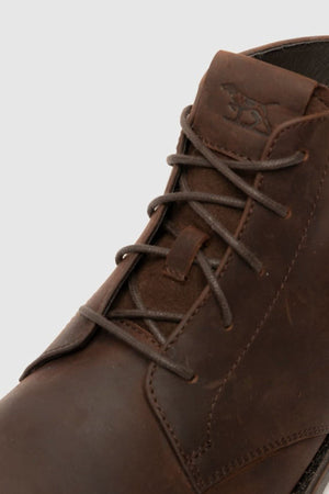 Close-up of the Rodd & Gunn Clearview Chukka Boot in brown USA crazyhorse leather, featuring dark brown laces, visible stitching, and an embossed animal logo on the tongue.
