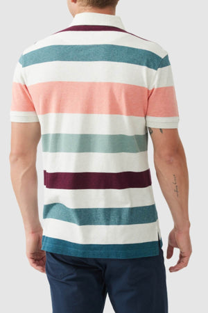 A man faces away, wearing the Rodd & Gunn Cambridge Sports Fit Polo with wide white, pink, teal, burgundy, and navy stripes—crafted from USA-grown cotton—and paired with dark blue pants.