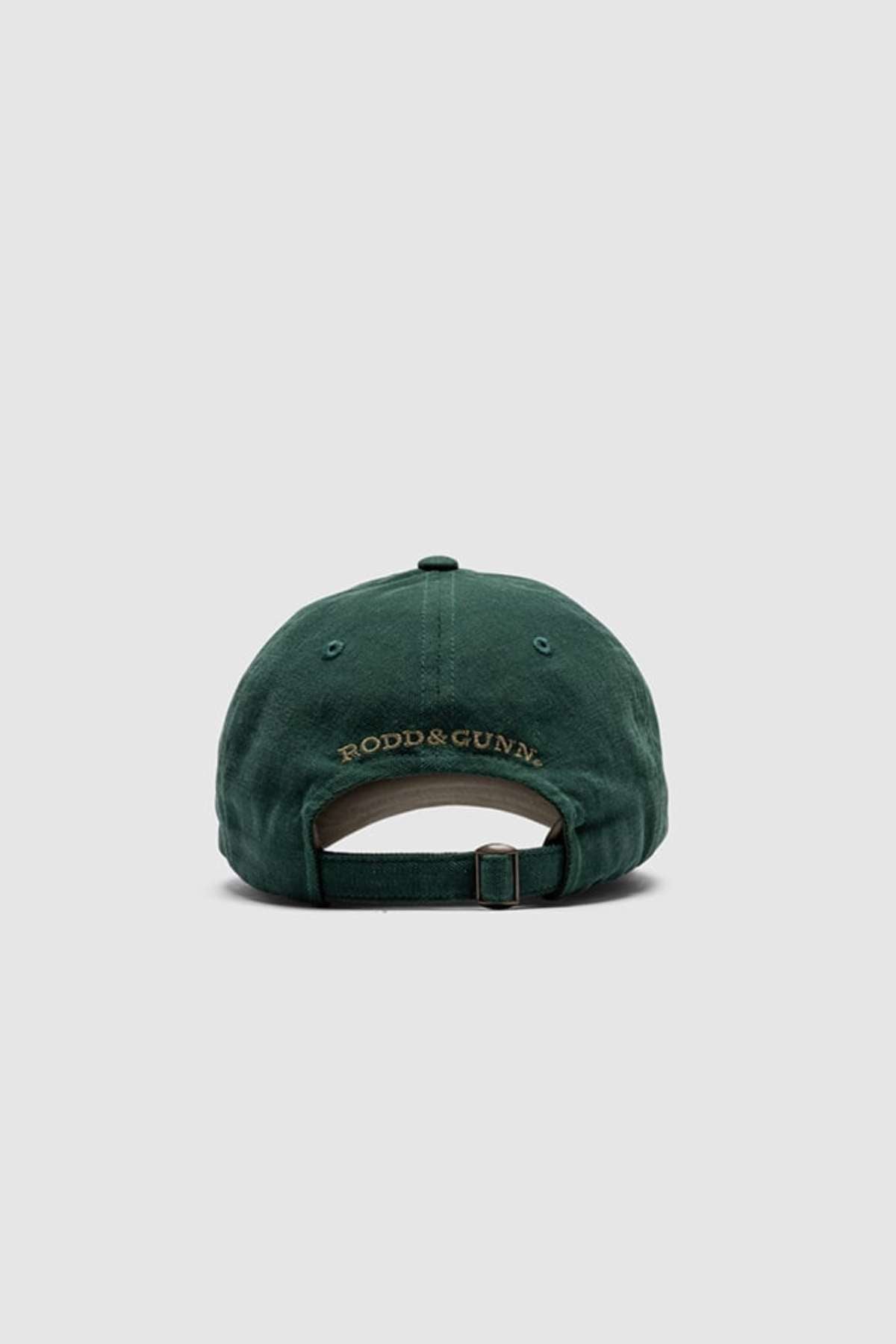 The Rodd & Gunn Signature Cap features a heavy-duty cotton twill on the back, an elegant gold "RODD & GUNN" embroidery, an adjustable strap, and a plain light gray background.