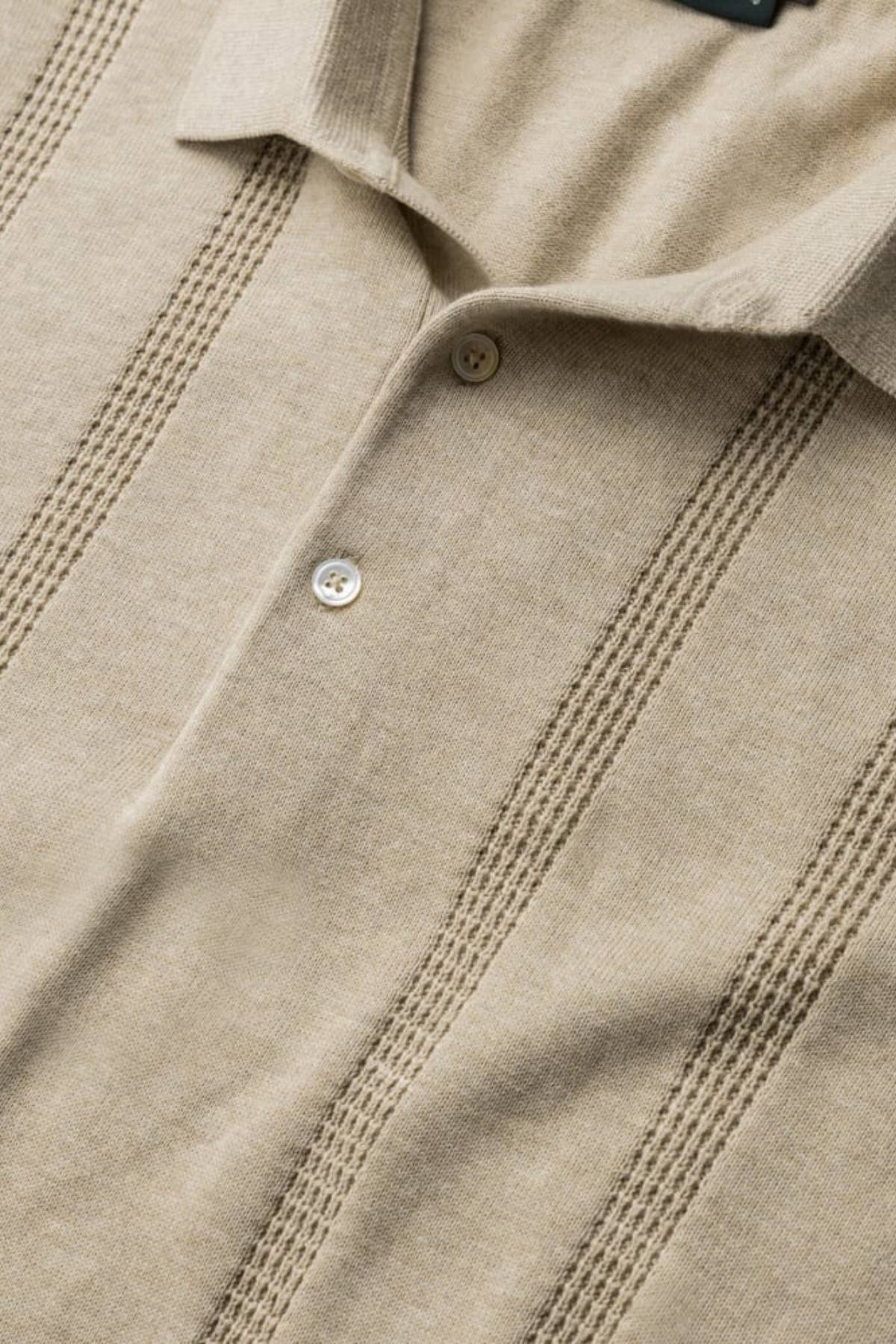 Close-up of the Rodd & Gunn Brooklands Knit, a beige Australian cotton polo shirt with a collar, two buttons, and vertical textured stripes for a slimming silhouette.