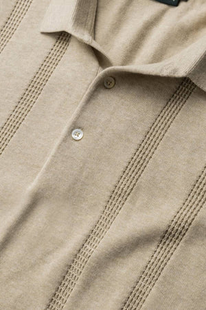 Close-up of the Rodd & Gunn Brooklands Knit, a beige Australian cotton polo shirt with a collar, two buttons, and vertical textured stripes for a slimming silhouette.