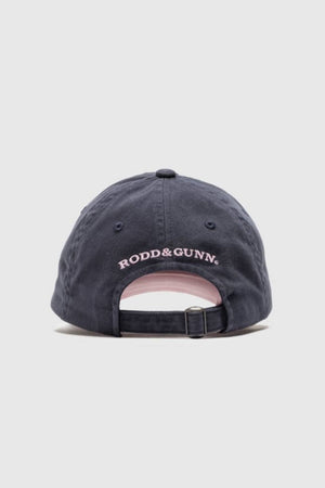 A navy blue Rodd & Gunn Gunn Cap Petite viewed from the back, featuring "RODD & GUNN" embroidered in pink above an adjustable strap with a metal buckle.