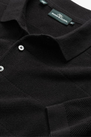 Close-up of a black textured cotton pique shirt with a collar, two white buttons, and the Rodd & Gunn Masons Flat Knit brand label inside the neckline.