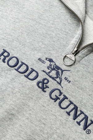 Close-up of the Rodd & Gunn Milford Sound Sweat in light gray, highlighting a premium YKK metal zip, navy "RODD & GUNN" logo, embroidered dog graphic, and "RECO. 1946" text above the logo.