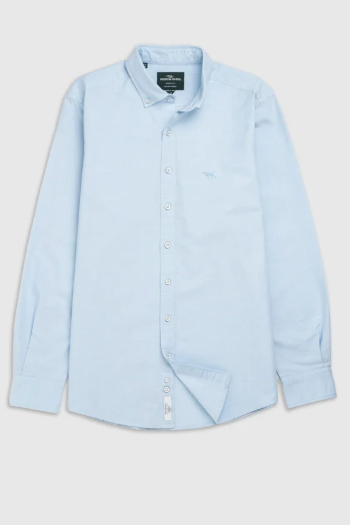 The Rodd & Gunn Gunn Oxford Sports Fit Shirt is a light blue men’s cotton shirt with long sleeves, a collar, and a subtle embroidered chest logo, displayed flat against a plain background.
