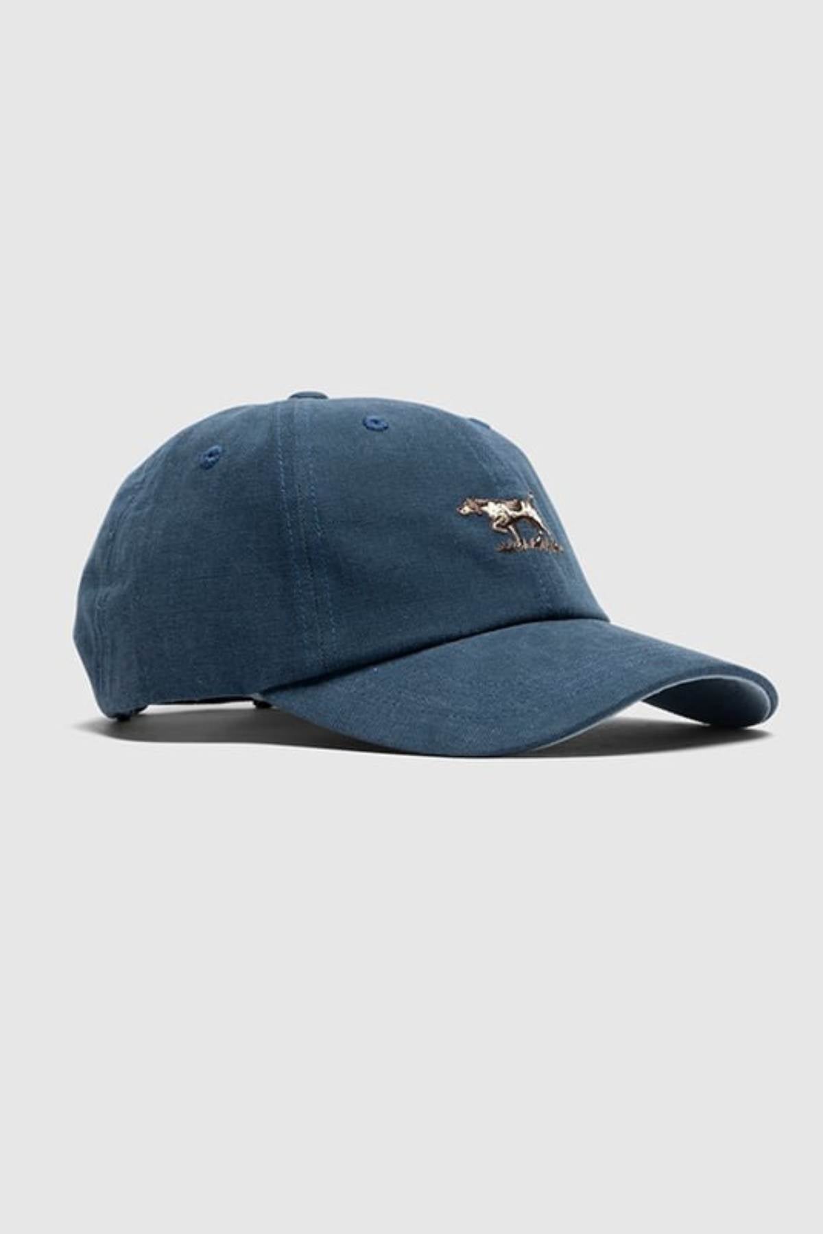 The Rodd & Gunn Signature Cap is a blue cotton twill hat with a curved brim and a small embroidered animal logo on the front, shown against a plain light gray background.