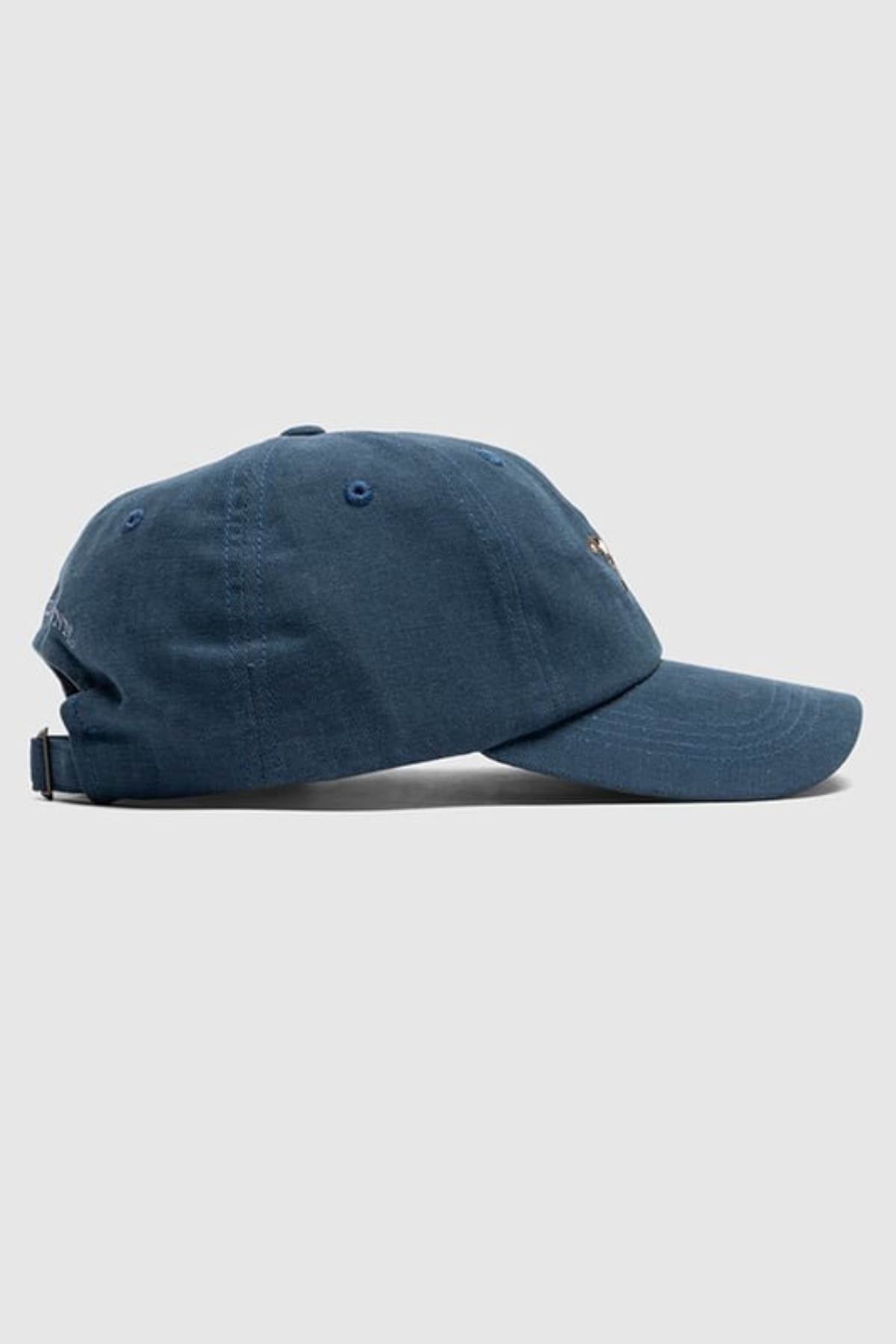 The Rodd & Gunn Signature Cap, made of blue cotton twill, is displayed in side profile on a light gray background. It has a curved brim, adjustable back strap, and features subtle Rodd & Gunn detailing.