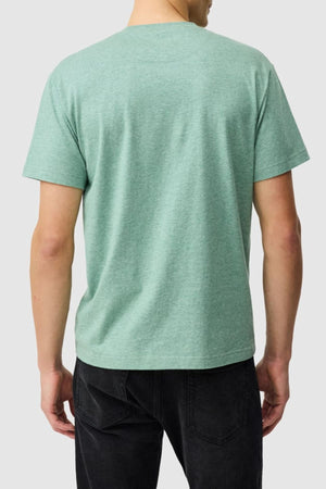 A person faces away from the camera in a Rodd & Gunn The Gunn Tee 2.0, a light green breathable sports fit jersey, and black jeans, set against a plain light gray background.