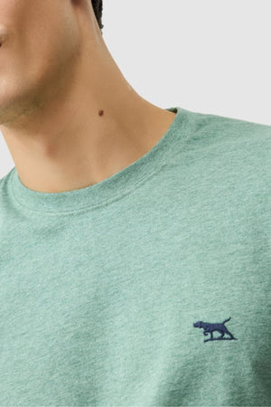 Close-up of someone in the Rodd & Gunn The Gunn Tee 2.0, a light green crew-neck sports fit made from breathable jersey with a small dark blue embroidered dog logo on the chest; their face is partially out of frame, showing a neck mole.