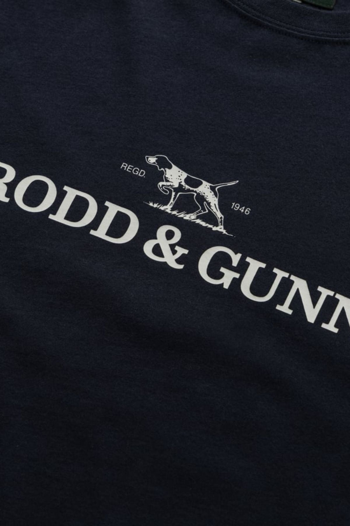 Close-up of the navy Rodd & Gunn The Logo Tee 2.0, crafted from 100% cotton, featuring a white pointing dog graphic above "RODD & GUNN" with "REGD" and "1946" on either side.