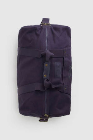 The Rodd & Gunn Ponsonby Road Duffle Bag in dark purple cotton canvas features a top zipper, side handle, and straps, shown against a plain light grey background.