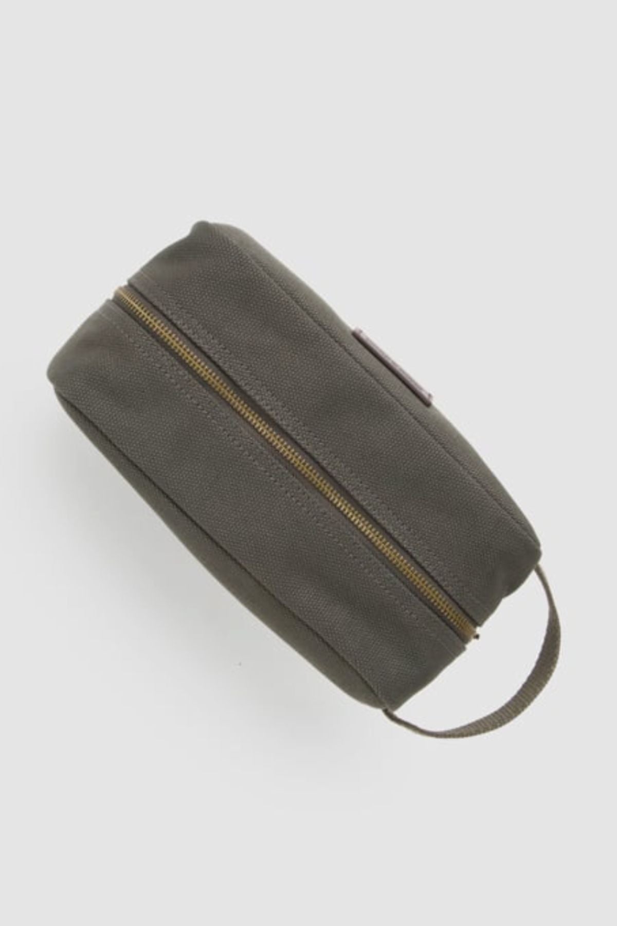 The Rodd & Gunn Ponsonby Wash Bag is a durable dark gray cotton canvas toiletry bag with a brown zipper and a small handle on one end, displayed against a plain light background.