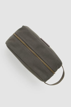 The Rodd & Gunn Ponsonby Wash Bag is a durable dark gray cotton canvas toiletry bag with a brown zipper and a small handle on one end, displayed against a plain light background.
