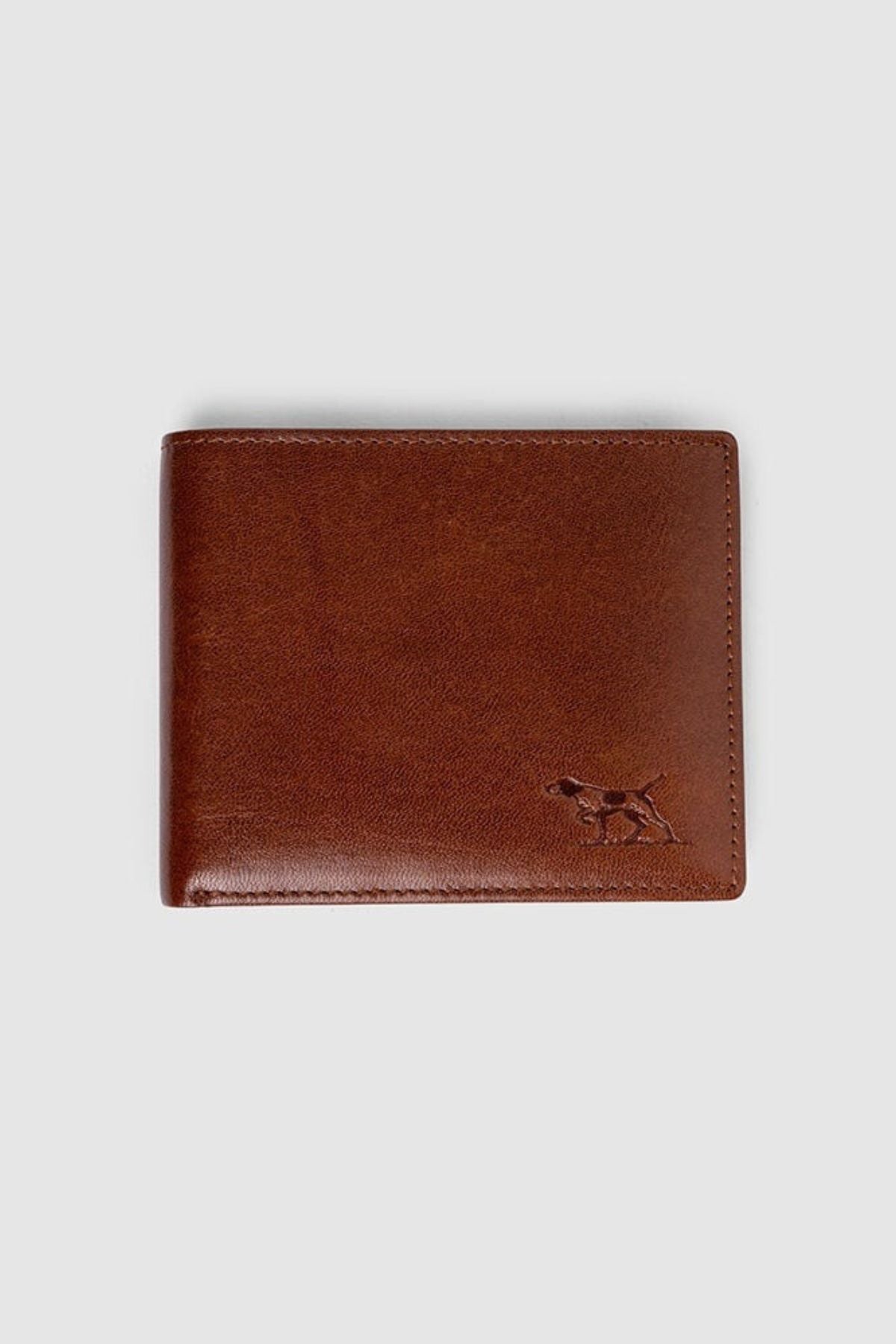 The Rodd & Gunn Wakefield Bi-Fold Wallet is crafted from brown Italian leather with stitched edges, an embossed dog in the bottom right corner, RFID protection, and is shown on a plain light gray background.