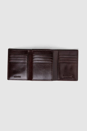 The Rodd & Gunn Westport Tri Fold Wallet in dark brown Italian leather is open, revealing multiple card slots and RFID-protected compartments against a plain light gray background.