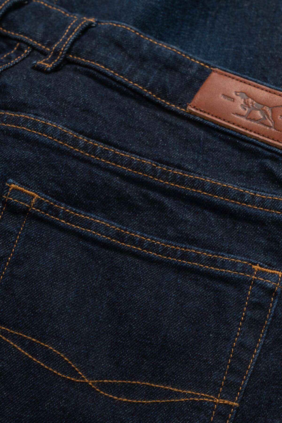 Close-up of the back pocket and waistband of the Rodd & Gunn Sutton Straight Italian Denim Jean, featuring signature stitching and a brown leather patch embossed with an animal logo.