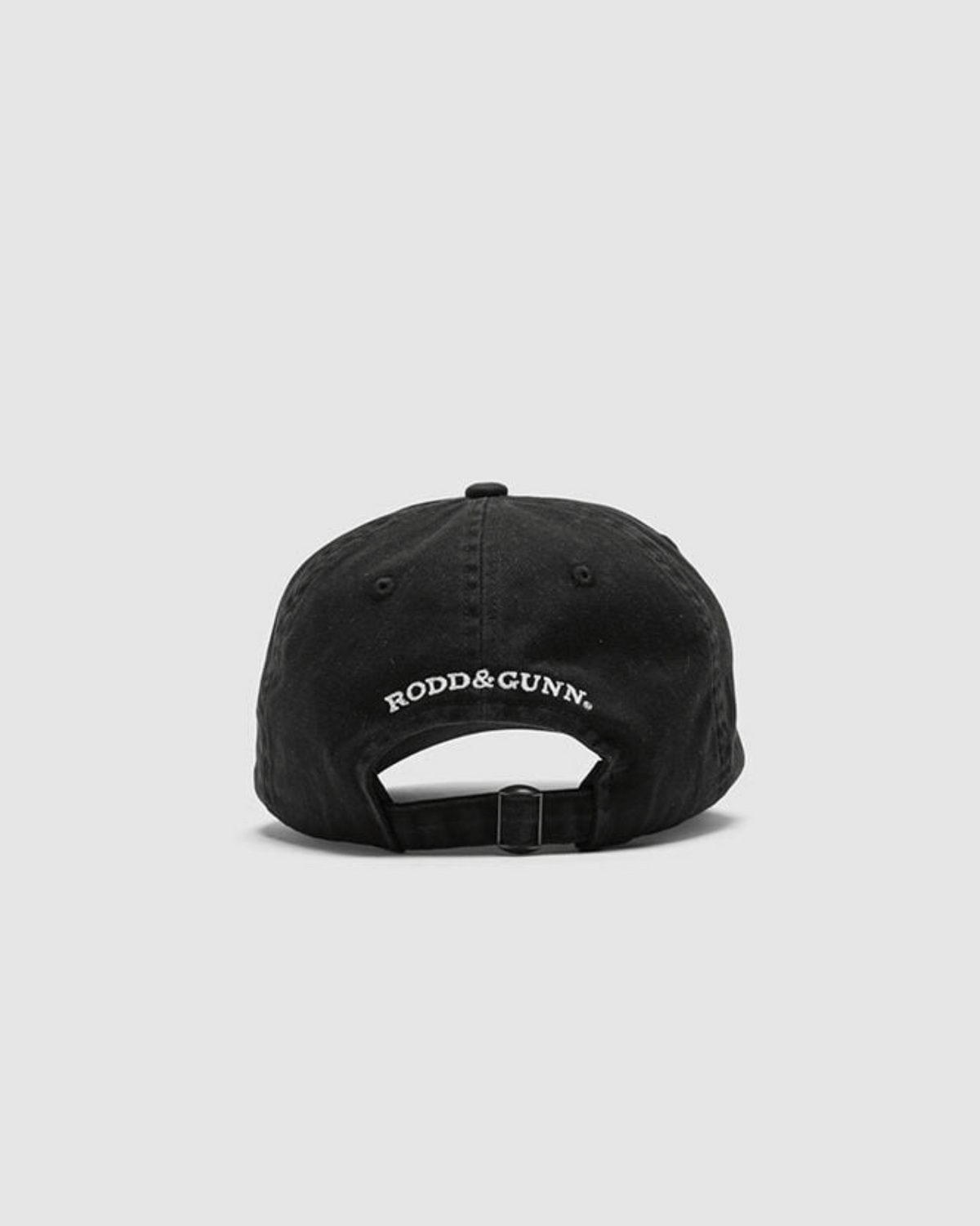 The image displays the Rodd & Gunn Gunn Cap, a black heavy-duty cotton twill cap with an adjustable strap and "RODD & GUNN" embroidered in white above the opening. It's set against a plain light gray background.