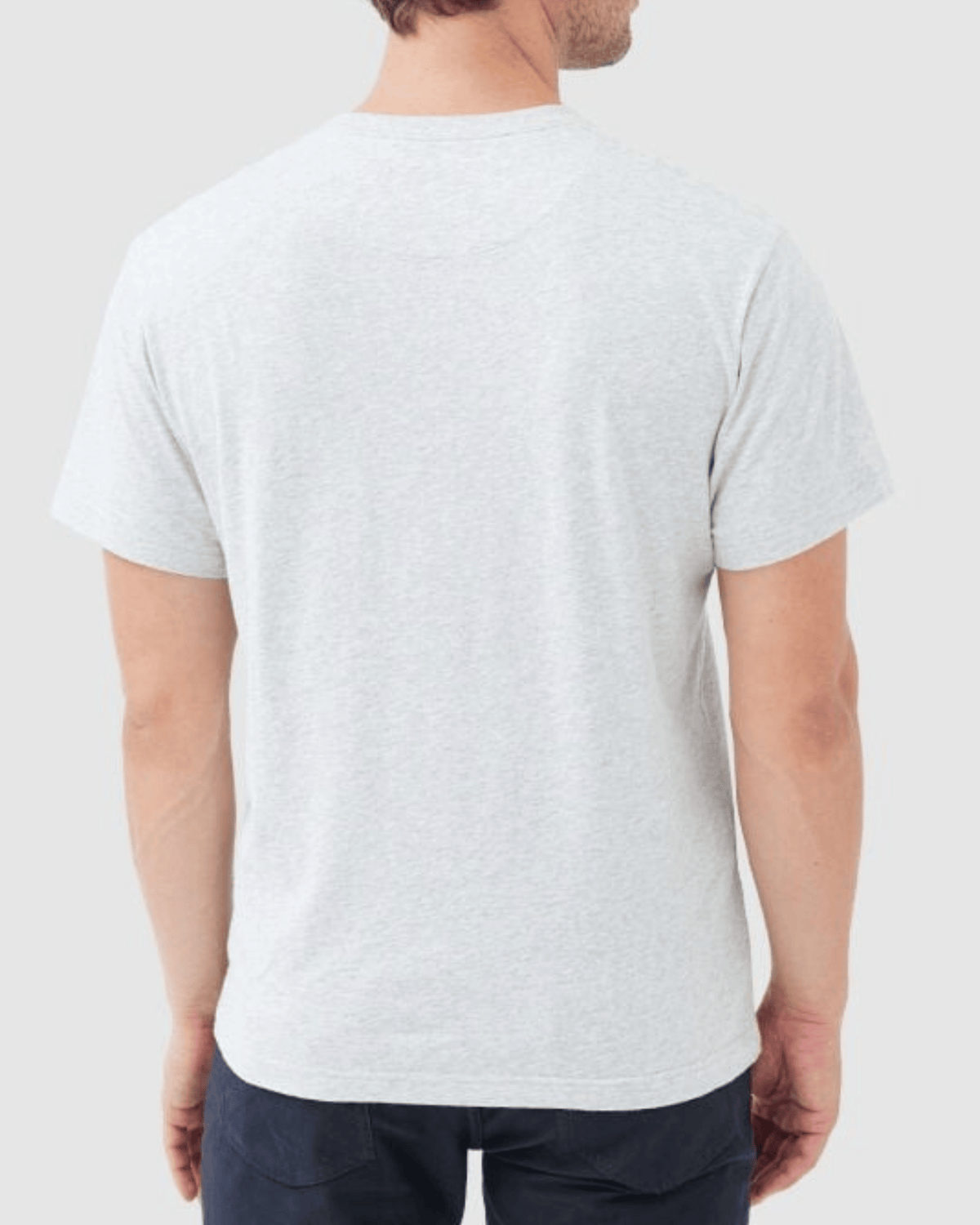 A man is seen from the back wearing the Rodd & Gunn The Gunn T-Shirt, a plain light gray casual tee crafted from soft Australian Cotton, paired with dark pants and standing against a light gray background.