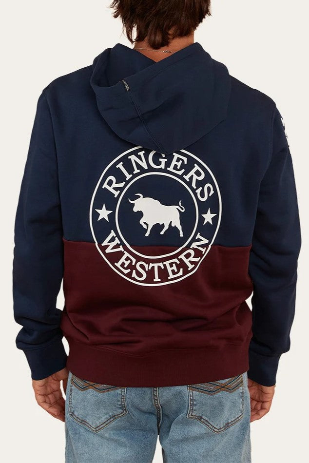 A person facing away from the camera wears a navy and maroon Ringers Western Hahndorf Hoodie with a bull graphic and logo on the back, plus a kangaroo pocket, paired with light blue jeans.