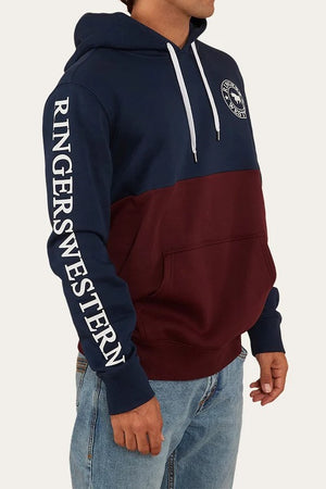 Wearing the Ringers Western Hahndorf Hoodie with its navy and maroon color-block design, sleeve branding, chest logo, kangaroo pocket, brushed fleece lining, and paired with light blue jeans.