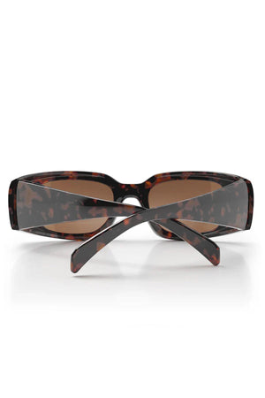 The SafeStyle Auras features a brown tort frame and brown polarised lenses in a rectangular style, made with shatterproof polycarbonate for durability. Displayed from the back with crossed arms.
