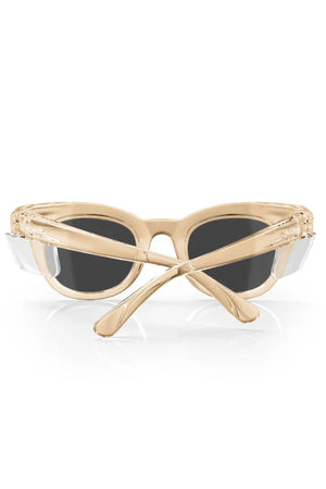The SafeStyle Harps sunglasses boast a chic champagne frame with polarised dark lenses offering UV protection. Seen from the front, their crossed arms rest elegantly on a reflective white surface.