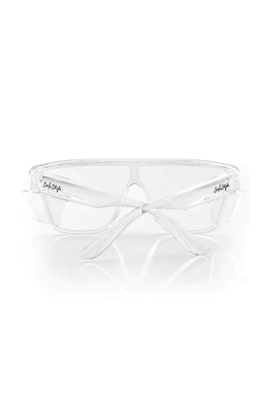 The SafeStyle Primes Clear Frame Clear Lens safety glasses feature a shatterproof frame and transparent, antiscratch lenses. Shown front-on with crossed arms against a white background, "SafeStyle" branding appears on the sides of the frames.