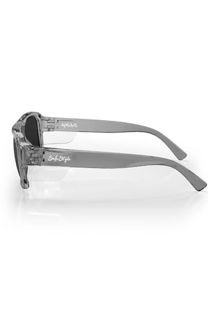 Side view of Safestyle Skylines Graphite Frame Grey Polarised Lens safety glasses with thick arms, dark UV400 lenses, and white SafeStyle logo on the arms. Glasses rest on a white surface.