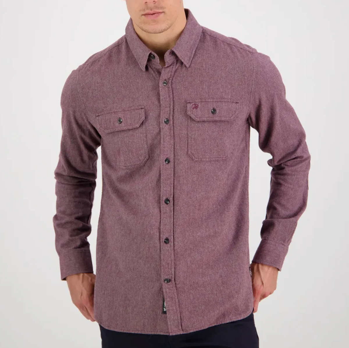 A person wearing the Swanndri Ranch Rd Shirt—stylish, long-sleeve, maroon, button-up with two front chest pockets and a tailored fit—stands against a plain white background.