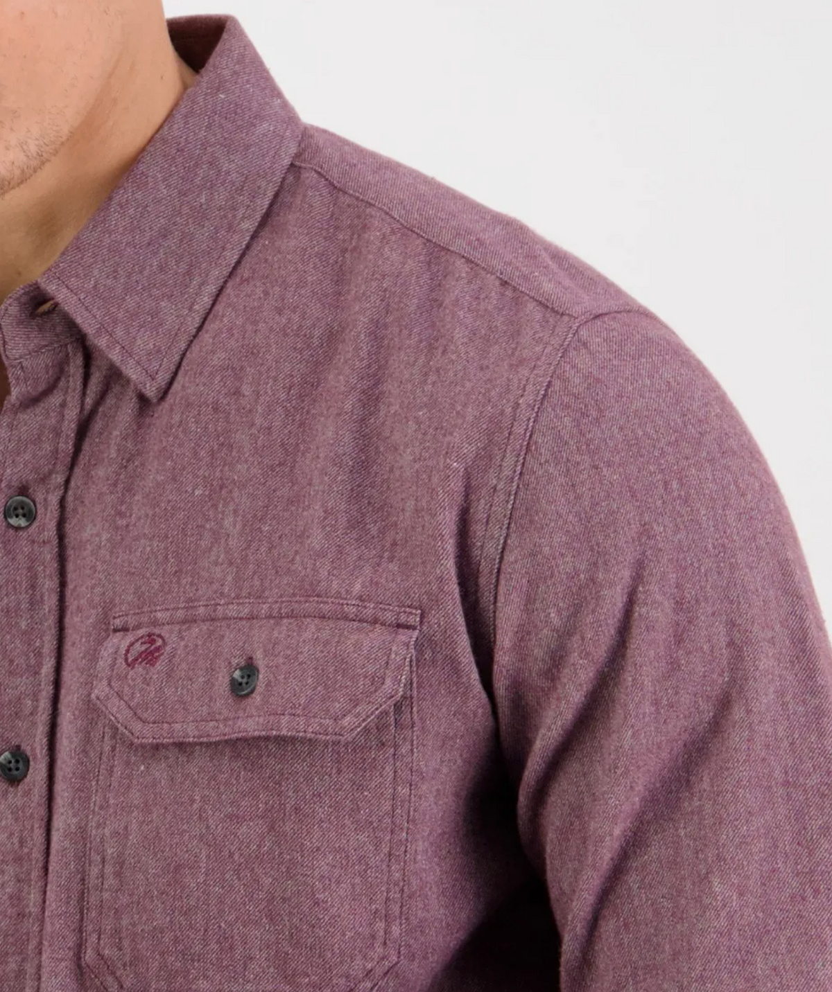 Close-up of a person wearing the Swanndri Ranch Rd Shirt—a stylish, long-sleeved, button-up purple shirt with a chest pocket and tailored fit. Only the lower face, neck, and upper torso appear against a plain light background.