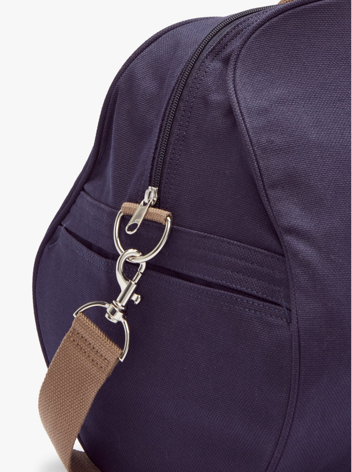 Close-up of an RM Williams Nanga Canvas Bag in navy blue with a silver zipper, hook clasp, and brown strap. Made from durable cotton, it has an exterior pocket with a subtle seam that highlights the fabric's texture and detail.