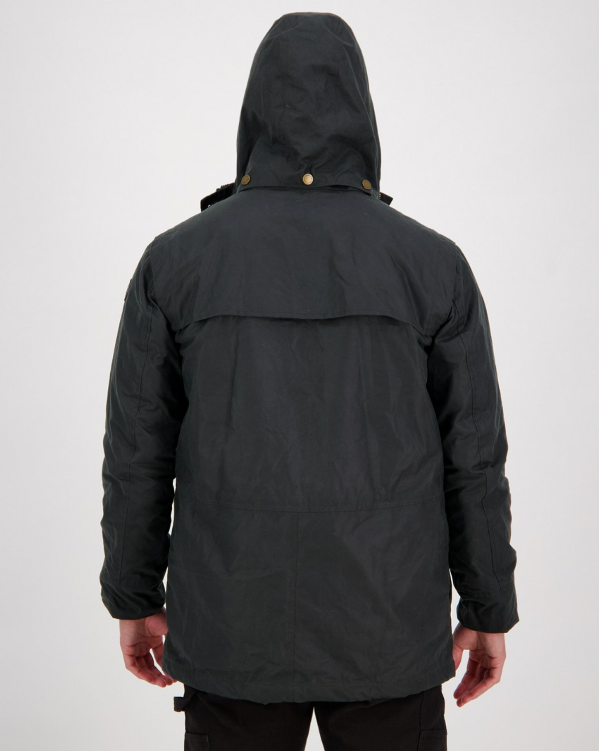 A person wearing a Swanndri Evans Flat Oilskin Jacket with button accents and a cape-like shoulder flap is seen from the back. The jacket has long sleeves, and the person wears dark pants against a plain white background.