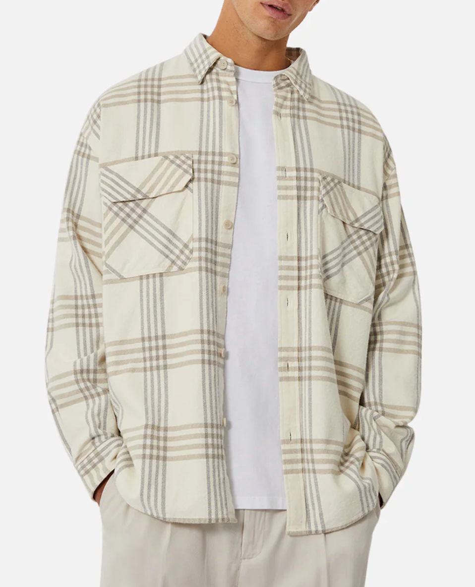 Someone wears the Industrie The Danville Shirt, a stylish regular-fit 100% cotton cream and beige plaid button-up, over a plain white t-shirt, with hands in light pants pockets, standing against a simple background.
