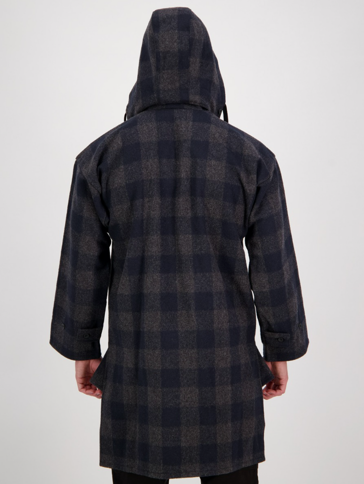 A person wearing the Swanndri Mosgiel Zip Front Bush Shirt, a hooded, long-sleeve dark plaid overshirt, stands with their back to the camera against a plain light background.