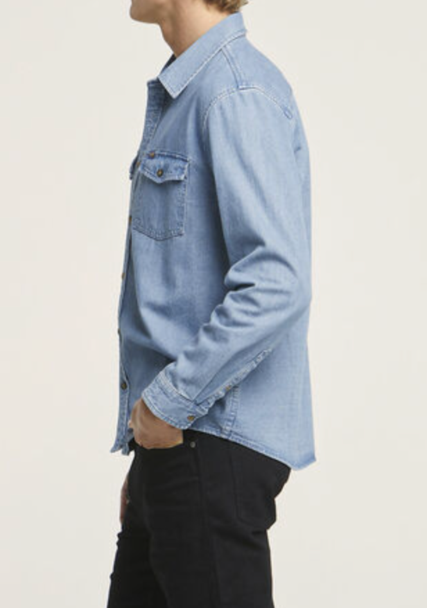 A person in a Wrangler Roadside Denim Shirt made of 100% cotton and black pants is shown in profile against a plain background, highlighting their upper body.