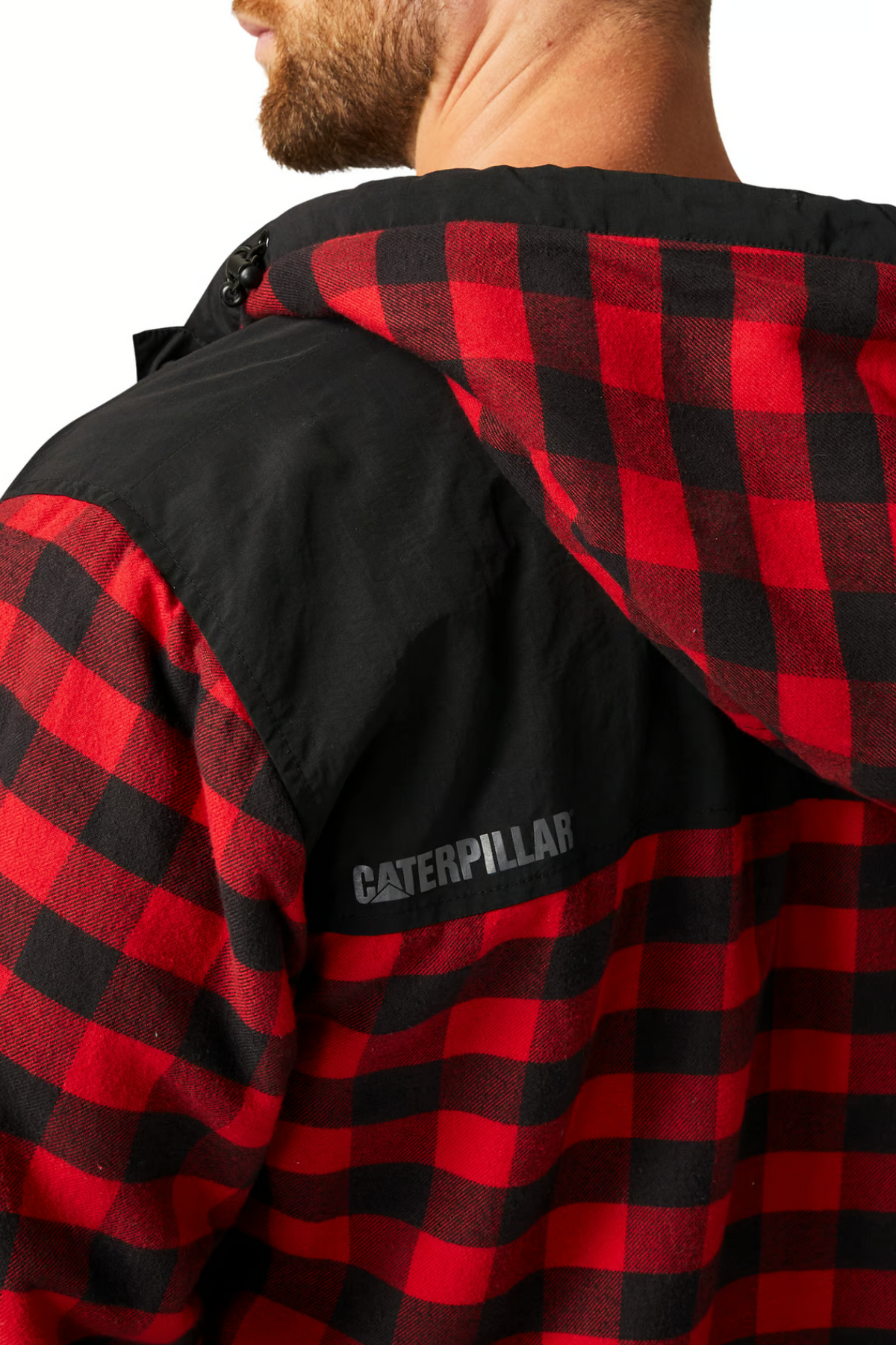 Someone is wearing the CAT Sequoia Shirt Jacket, a red and black checkered cotton jacket with a cozy fleece lining and black hood. "Caterpillar" is visible on the upper back as they face away from the camera, partially visible from the shoulders up.