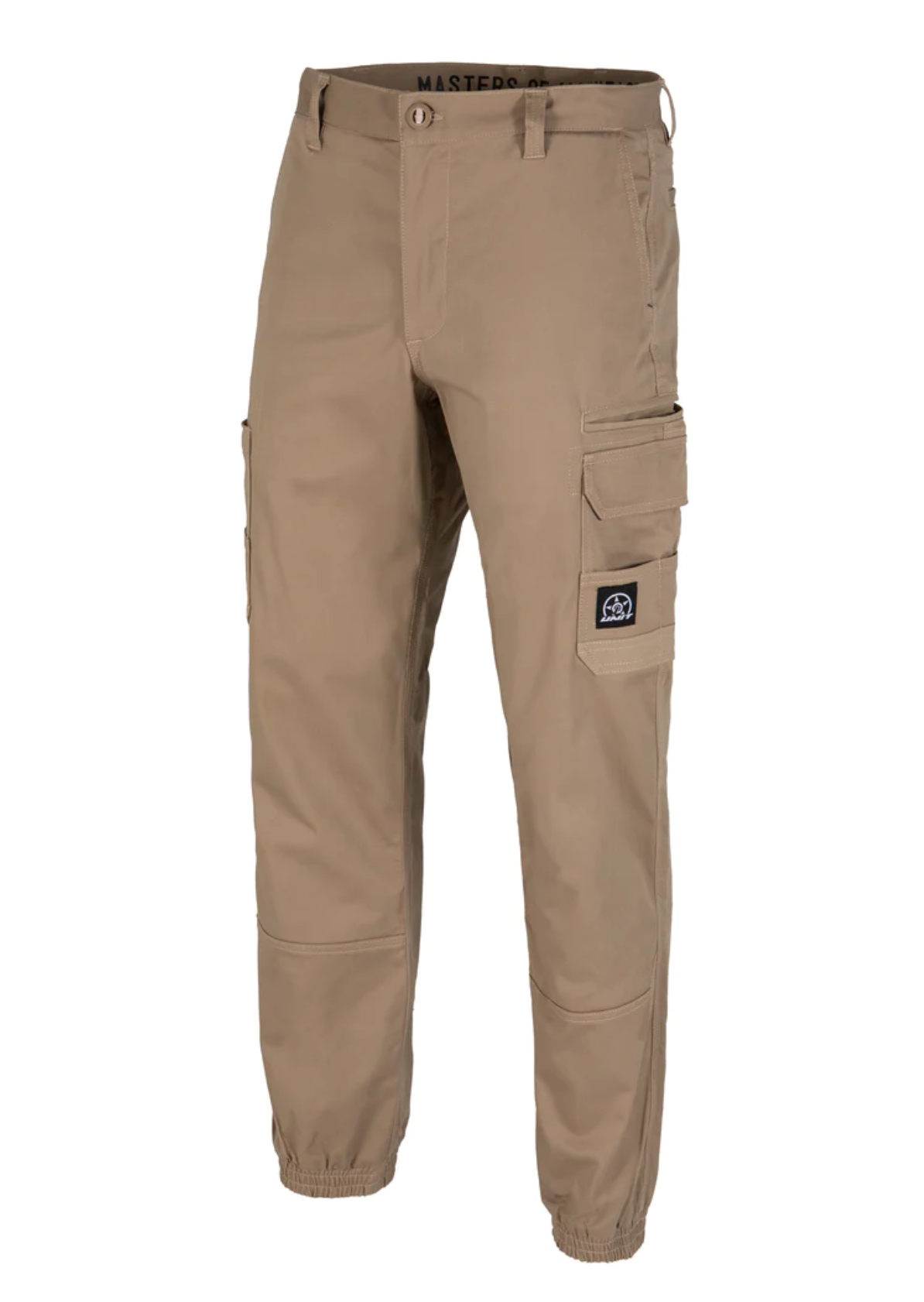 The UNIT Demolition Cargo Cuffed Pant features tan stretch fabric, multiple pockets including large cargo-style side pockets, a button and zipper closure, elastic waistband and cuffs. It has a small black patch with a white logo on the right pocket.