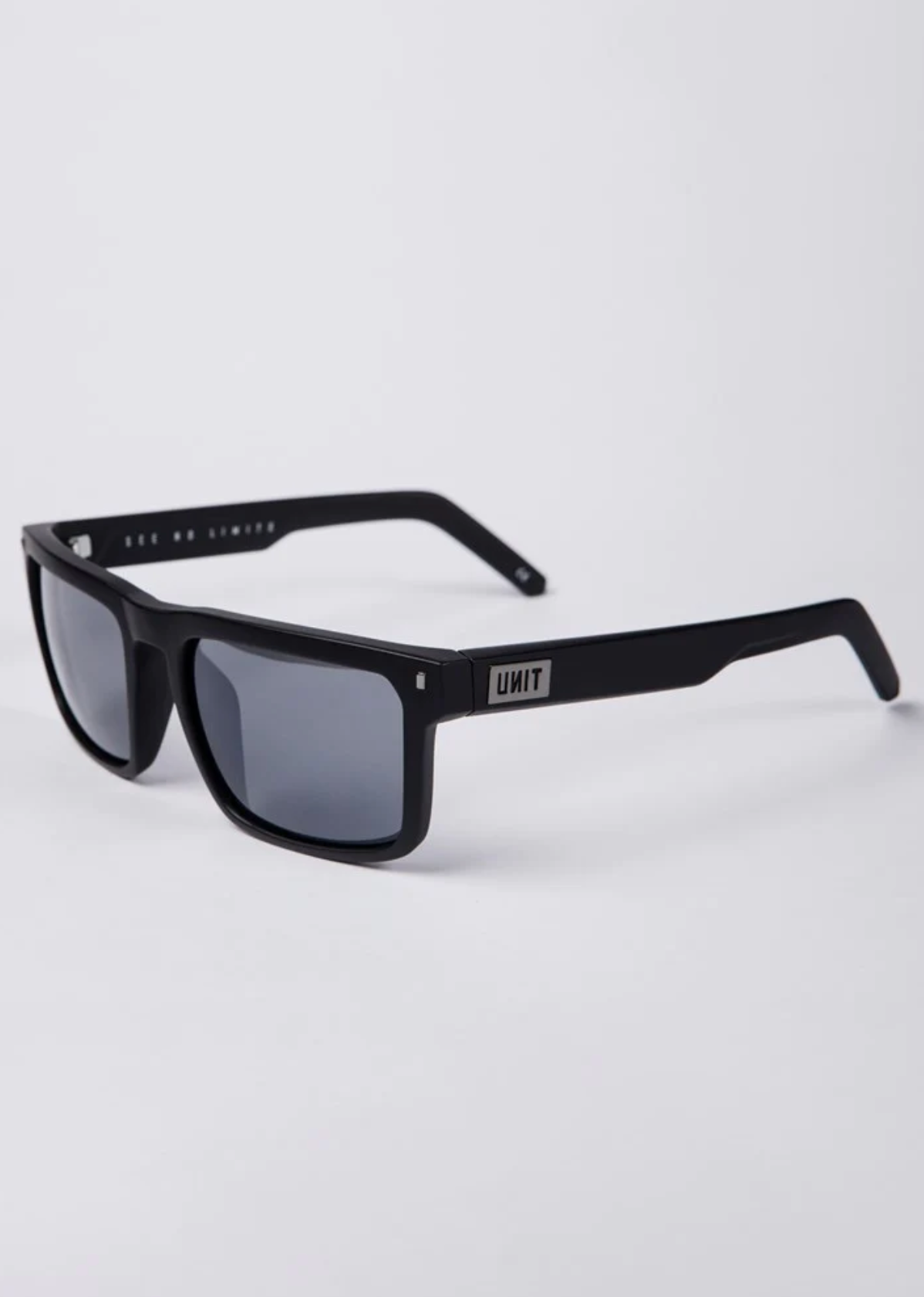 UNIT Primer Polarised Eyewear: Black rectangular sunglasses with dark polarised lenses, lightweight thick frame, and metallic "UNIT" logo on the temple for superior UV protection. Displayed on a white background.