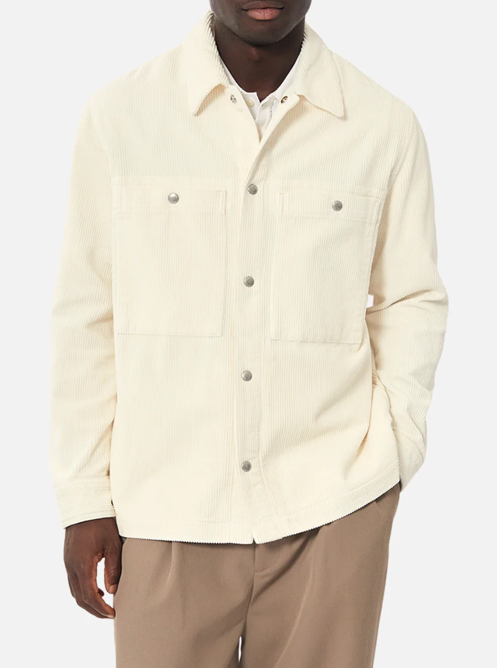 Someone wearing the Industrie The Atmore Jacket, a stylish cream-colored corduroy piece with button closures and two chest pockets. This 100% cotton jacket is paired with light brown trousers, set against a plain white background.
