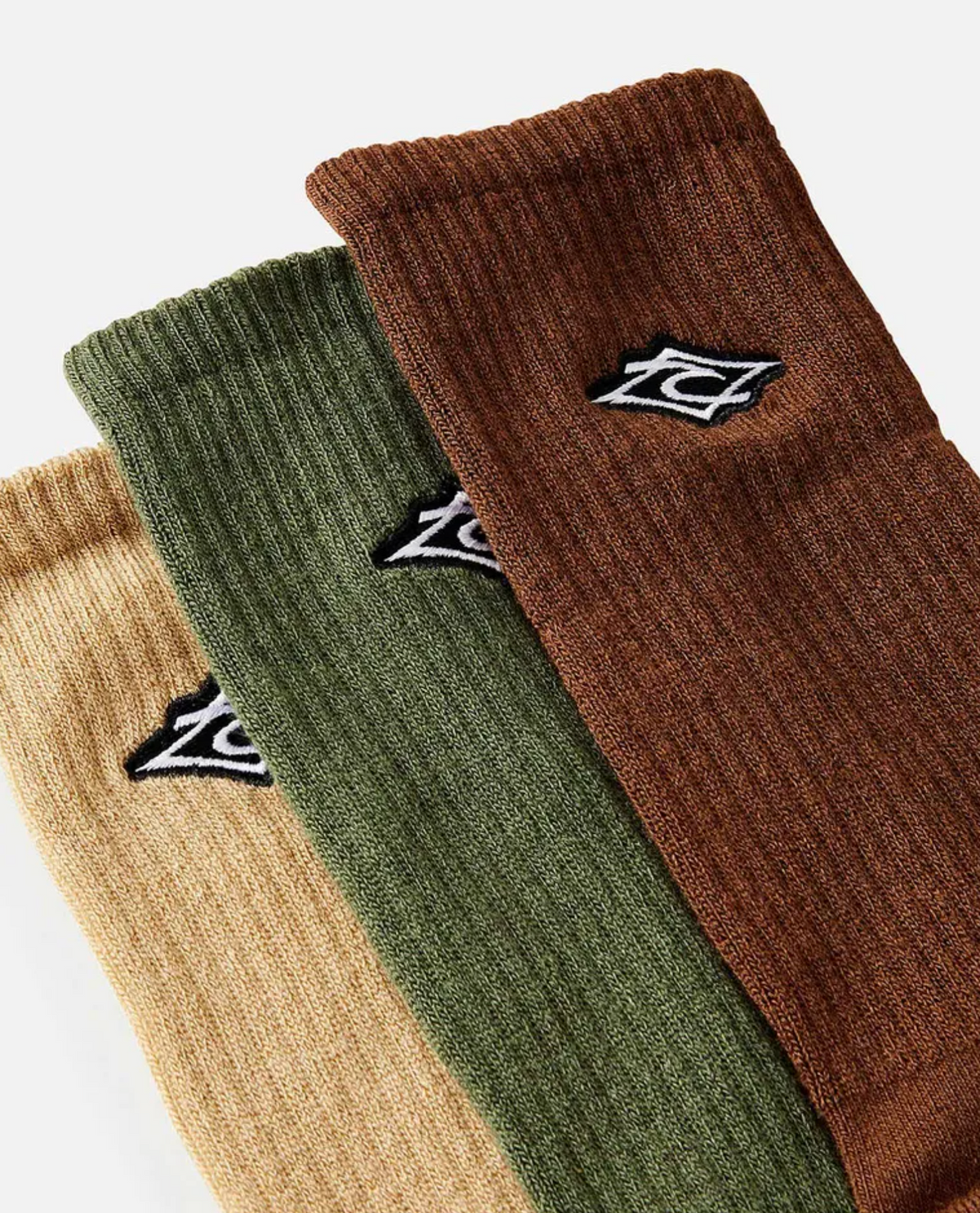 The Rip Curl Diamond Crew Sock 3 Pack, featuring arch support for comfort, includes three ribbed socks in beige, green, and brown with small embroidered logos. They are displayed side by side on a plain background.