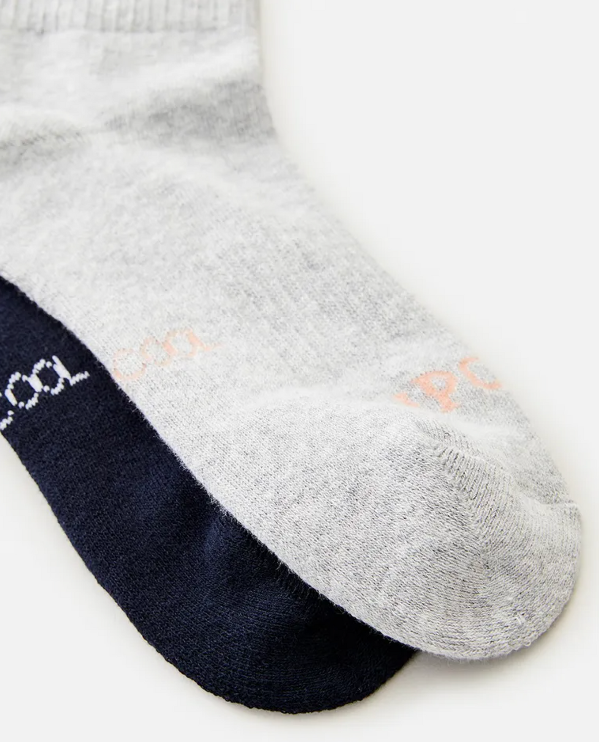 A close-up image of two Rip Curl Womens VaporCool Sport Socks, one gray and one black, overlapping each other on a flat surface. The gray sock is on top with "XPOO" faintly visible near the toes. The black sock underneath has similar text, partially hidden. These socks feature moisture-wicking technology for optimal comfort.