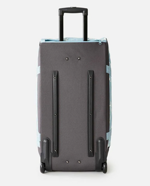 Rear view of a gray Rip Curl Jupiter 80L Travel Bag with a telescopic handle, blue accents, and two wheels crafted from recycled polyester, standing upright against a white background.