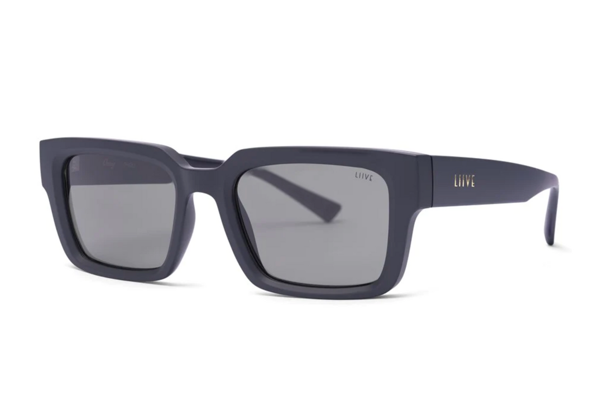 Liive Oney Sunglasses feature rectangular, matte dark grey polycarbonate frames with thick arms, grey tinted lenses, and "LIIVE" in gold on the left arm—combining bold style with UV protection.