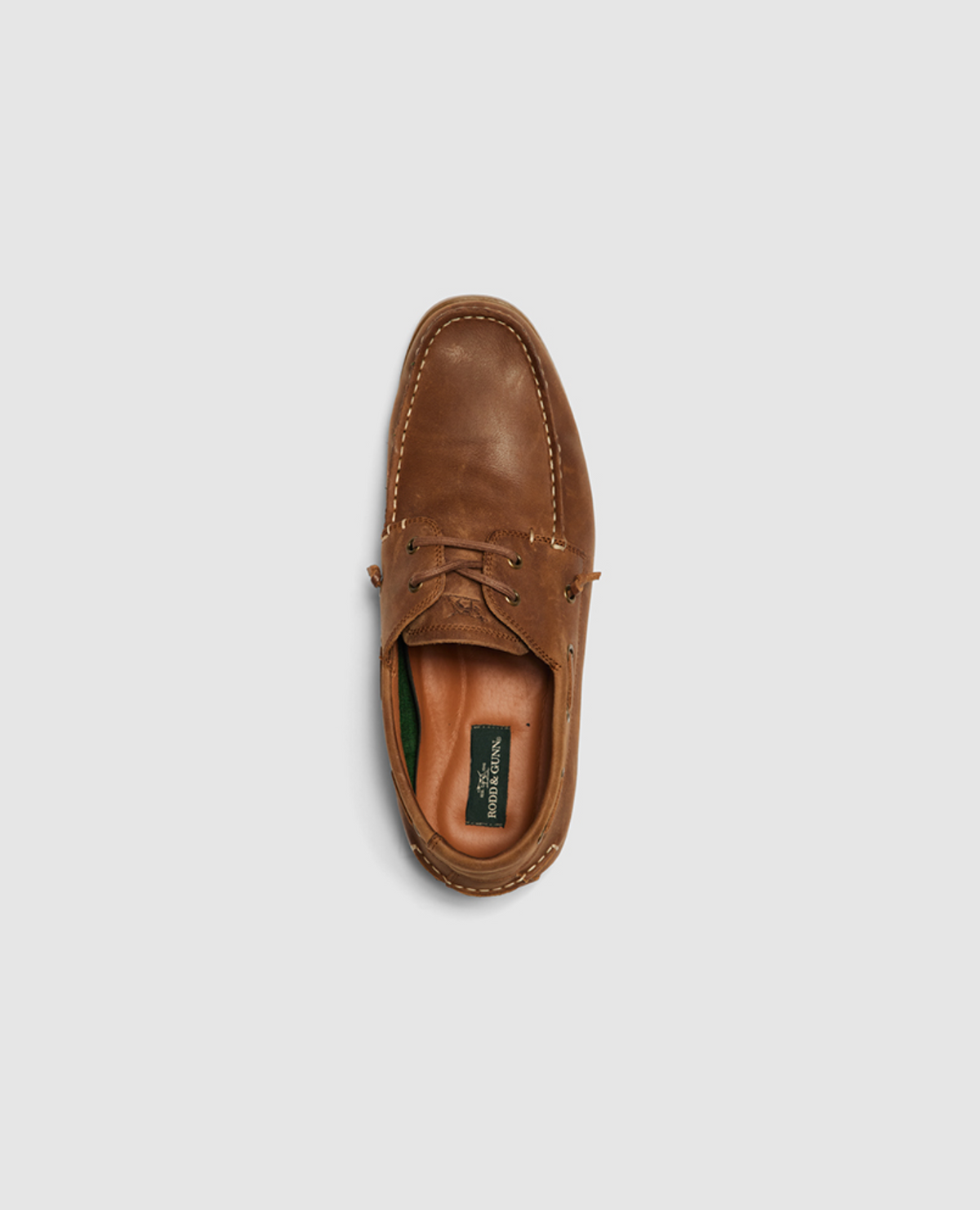 Top view of the Rodd & Gunn Gordons Bay Boat Shoe in brown leather on a light gray background. The design features a leather upper with visible stitching, lace-up detail, and a green insole with the brand label. A durable rubber outsole completes its classic look for any casual occasion.