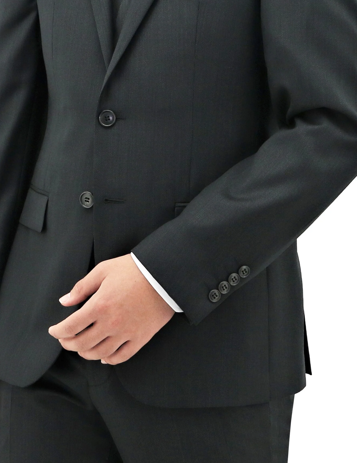 A close-up shot of an individual donning the Boston Michel Jacket, crafted entirely from luxurious Australian Merino Wool. Beneath the jacket, a white shirt peeks out at the cuffs. The person’s right arm is gently bent, with their hand casually resting in front of them. The suit jacket boasts three visible buttons and a pocket on the right side.