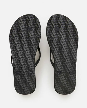 A pair of Rip Curl Sun Tribe Bloom Thongs in black, shown from the bottom with wavy textured soles, small circular logos near the heels and forefoot, and an ergonomic molded rubber strap for comfort.