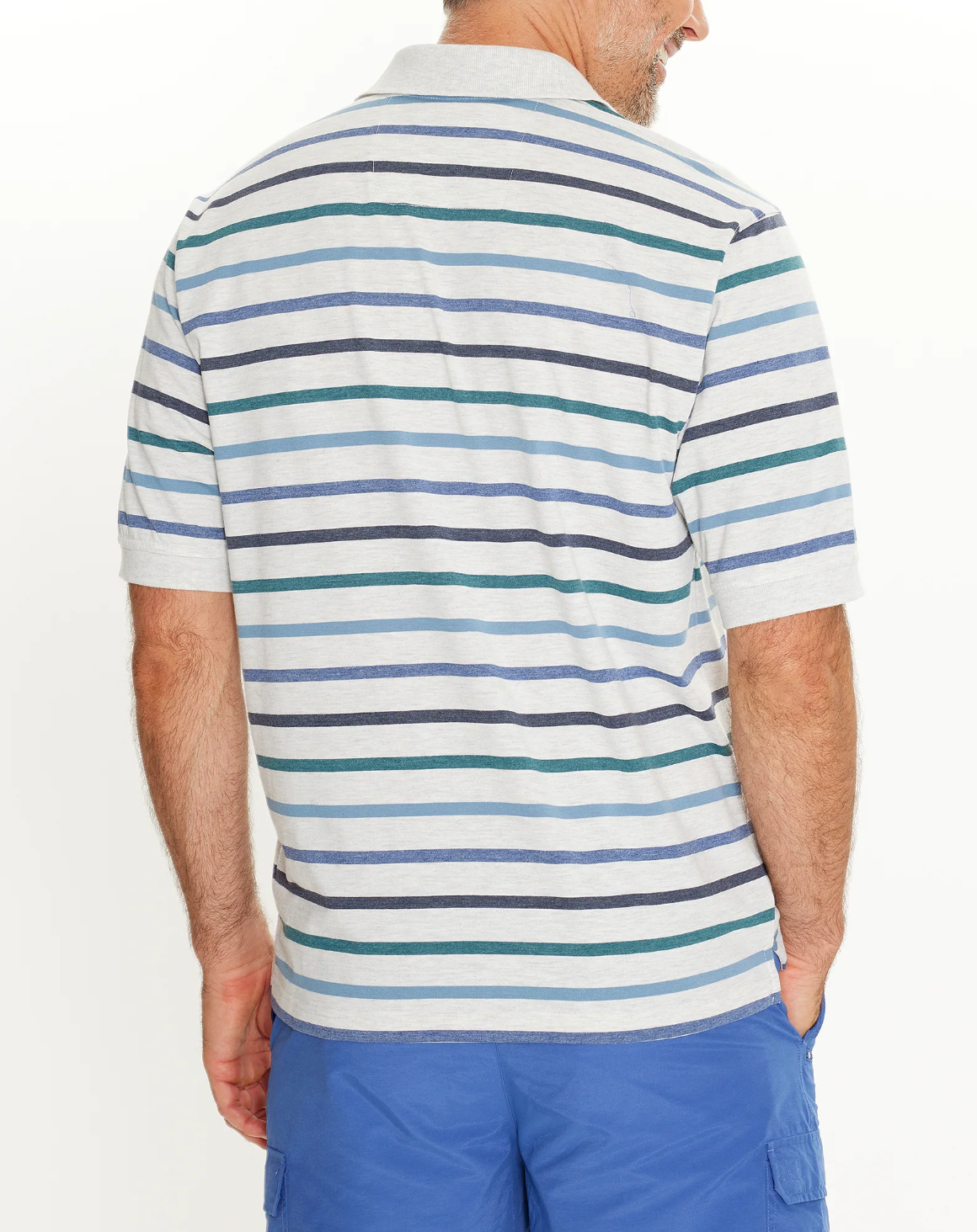 A man is wearing the Breakaway Ozi Kinnersly Polo, featuring horizontal blue, green, and white stripes with a rib knit collar. He's seen from the back, paired seamlessly with casual blue shorts.