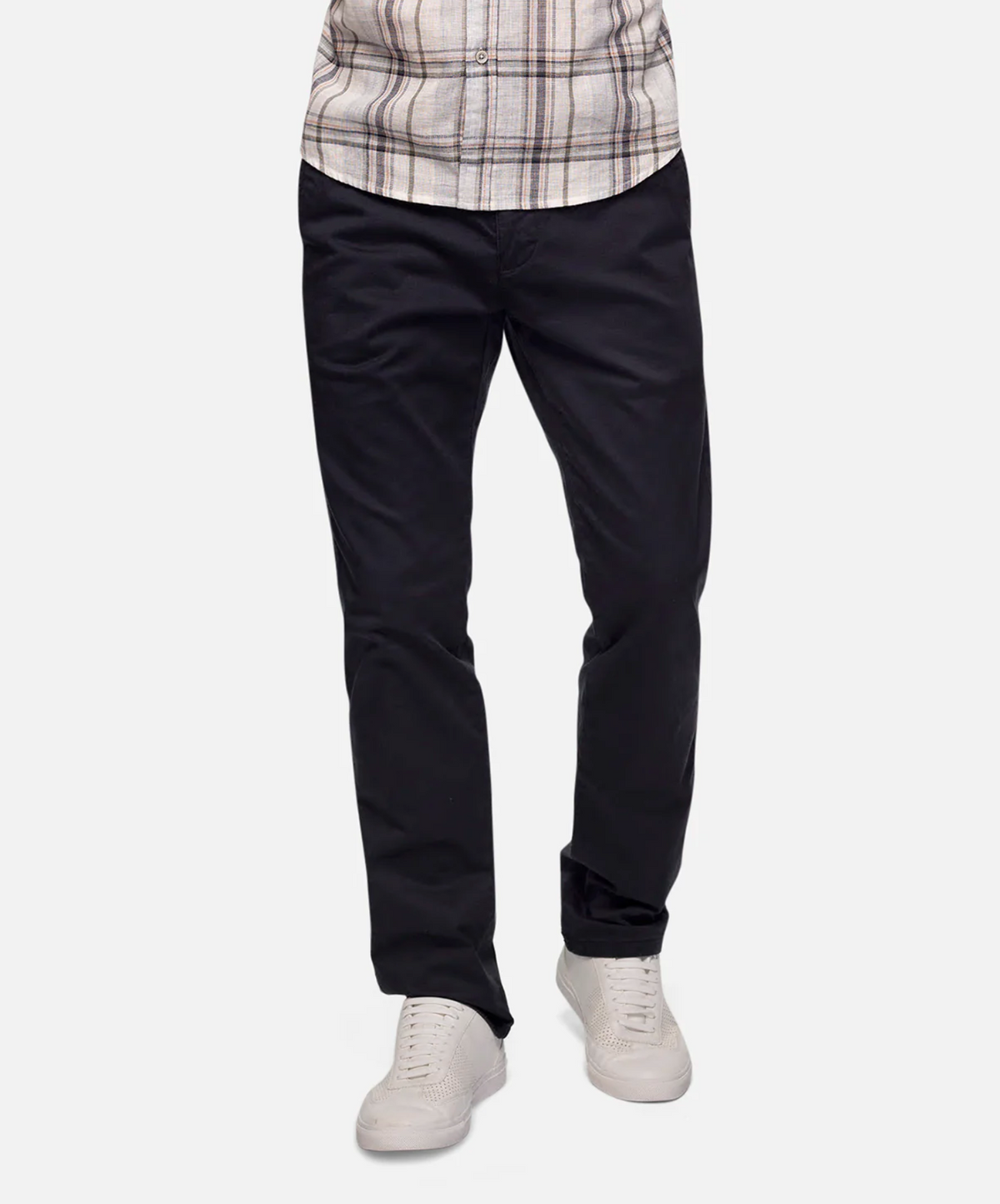 A person is wearing a pair of Industrie The Regular Cuba Chino Pants in black with side pockets, a plaid shirt, and white sneakers. The image shows from the waist down, focusing on the clothing and footwear against a plain white background.