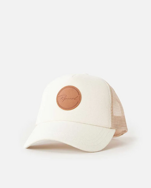 The Rip Curl Premium Surf Trucker cap features a beige and tan design with mesh, a curved brim, and a round leather patch bearing cursive writing. Made from cotton, this stylish accessory is shown on a plain white background, ideal for fans of Rip Curl.