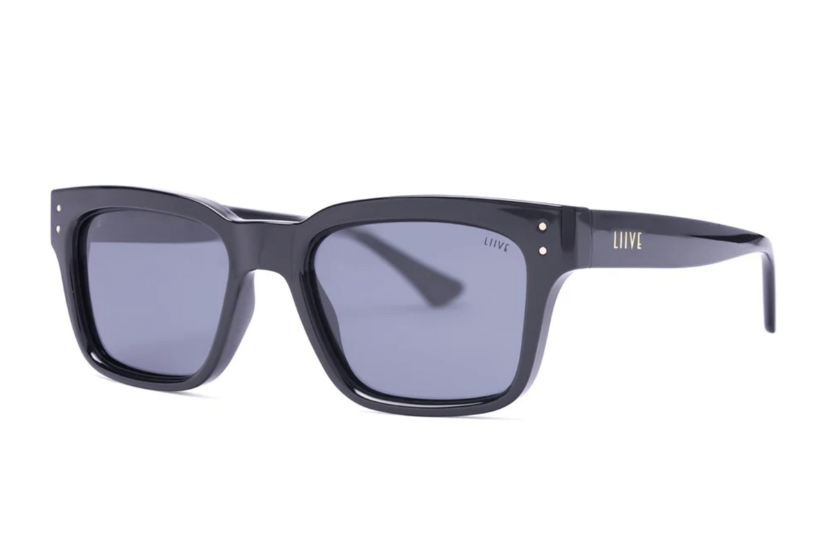 Liive Dan Polar Sunglasses are rectangular, black with dark lenses and a glossy polycarbonate finish. The durable frame includes UV protection, subtle metal accents near the hinges, and a small brand logo on the side of the arms.